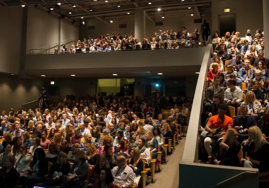 Audience seated in a large auditorium.